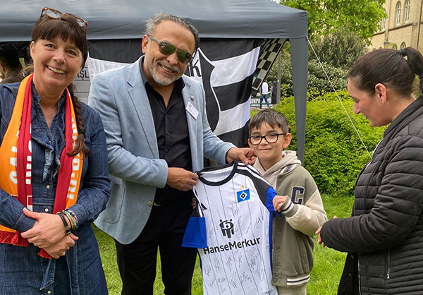 Claudia Unruh und Önder Zeybek überreichen Jamens ein HSV-Trikot mit Unterschriften